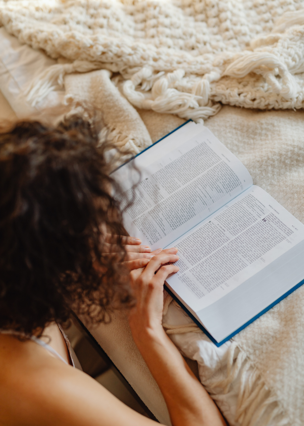 woman reading the bible on her bed